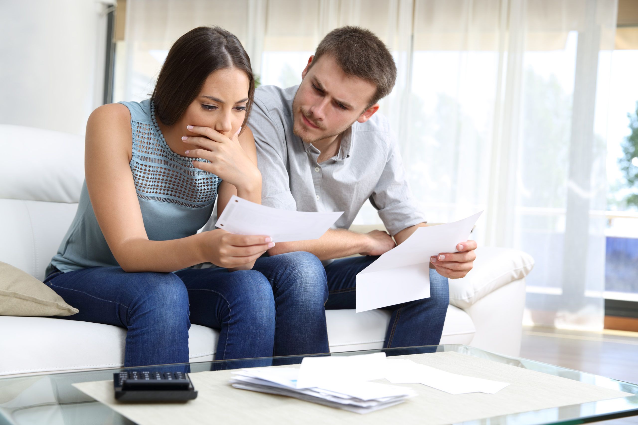 Worried couple checking receipt sitting at home